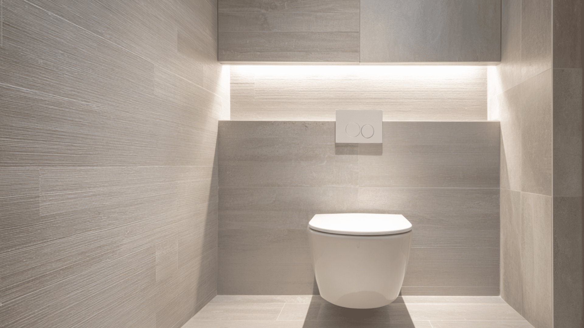 A bathroom featuring a wall-hung toilet and a light fixture positioned above it