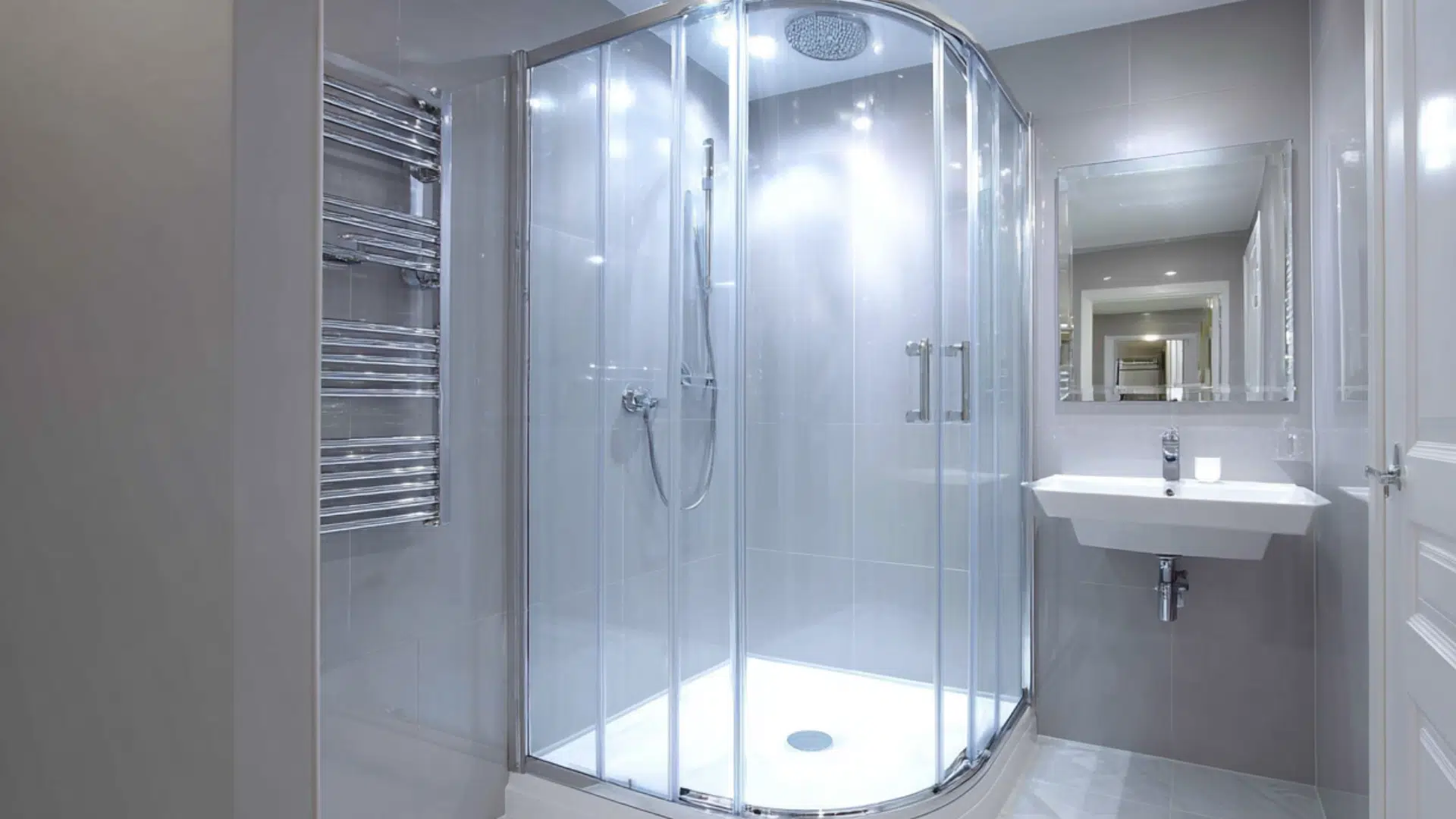A modern bathroom featuring a corner glass shower stall and a sleek sink