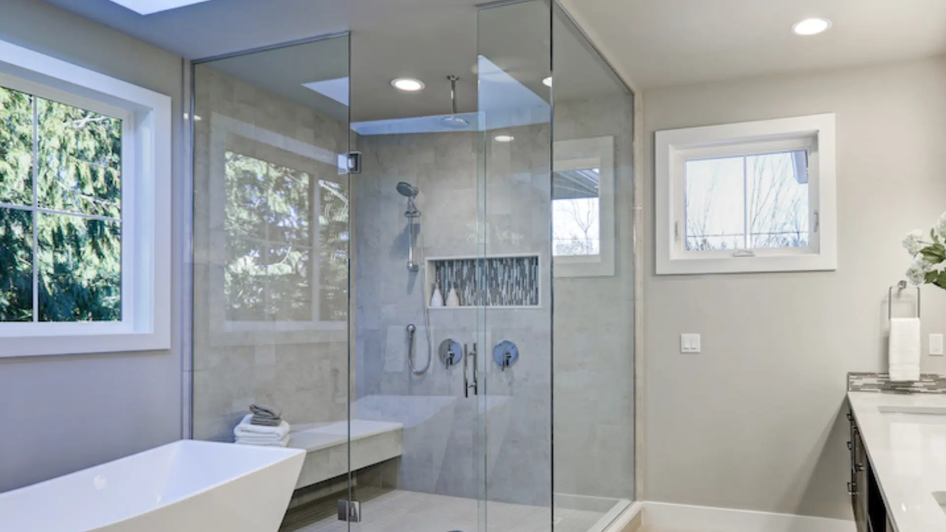 A modern bathroom featuring a frameless shower screen, sink, and toilet, showcasing a clean and minimalist design