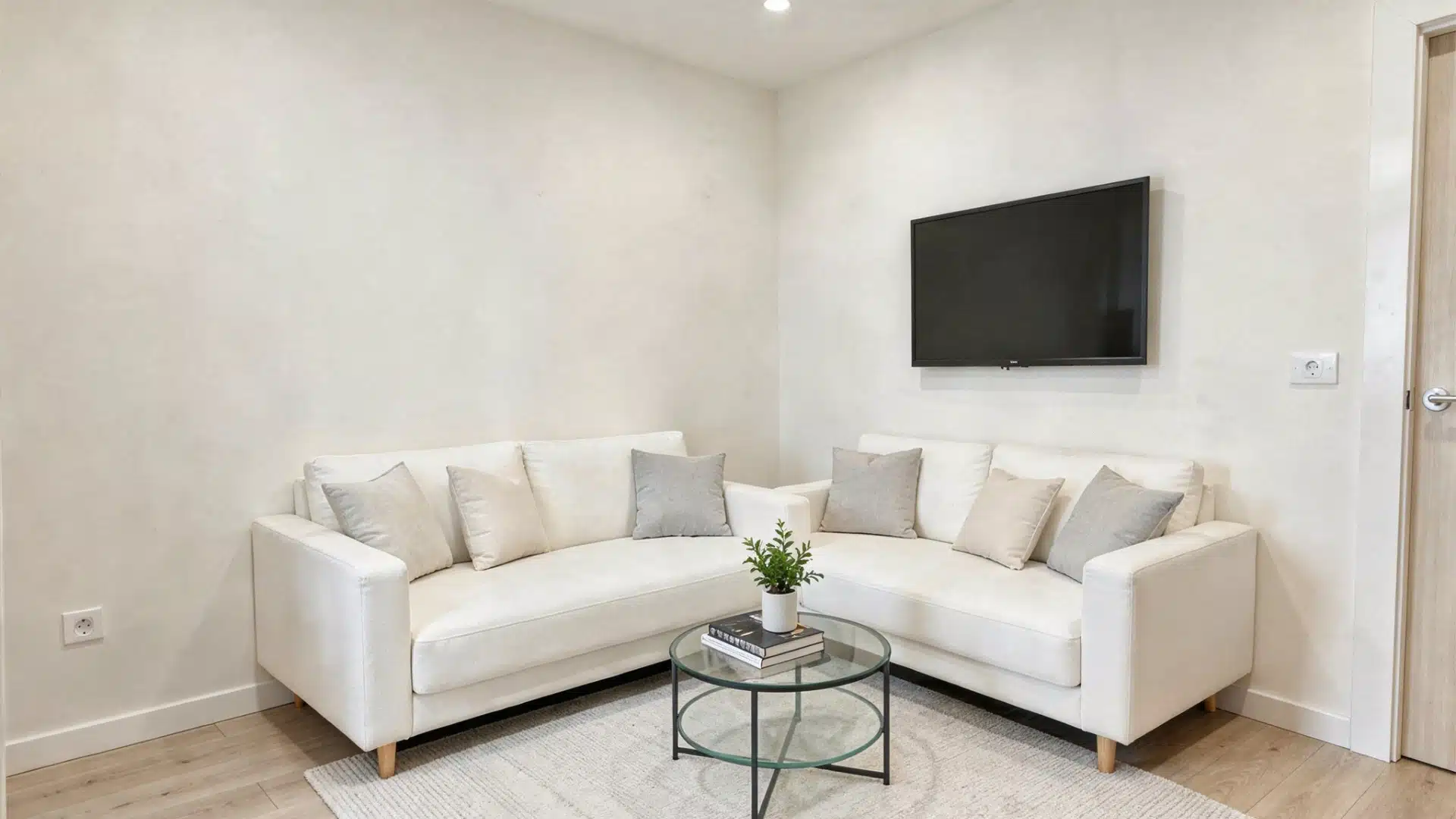 A white couch and chair arranged in a cozy room, featuring neutral walls and soft lighting