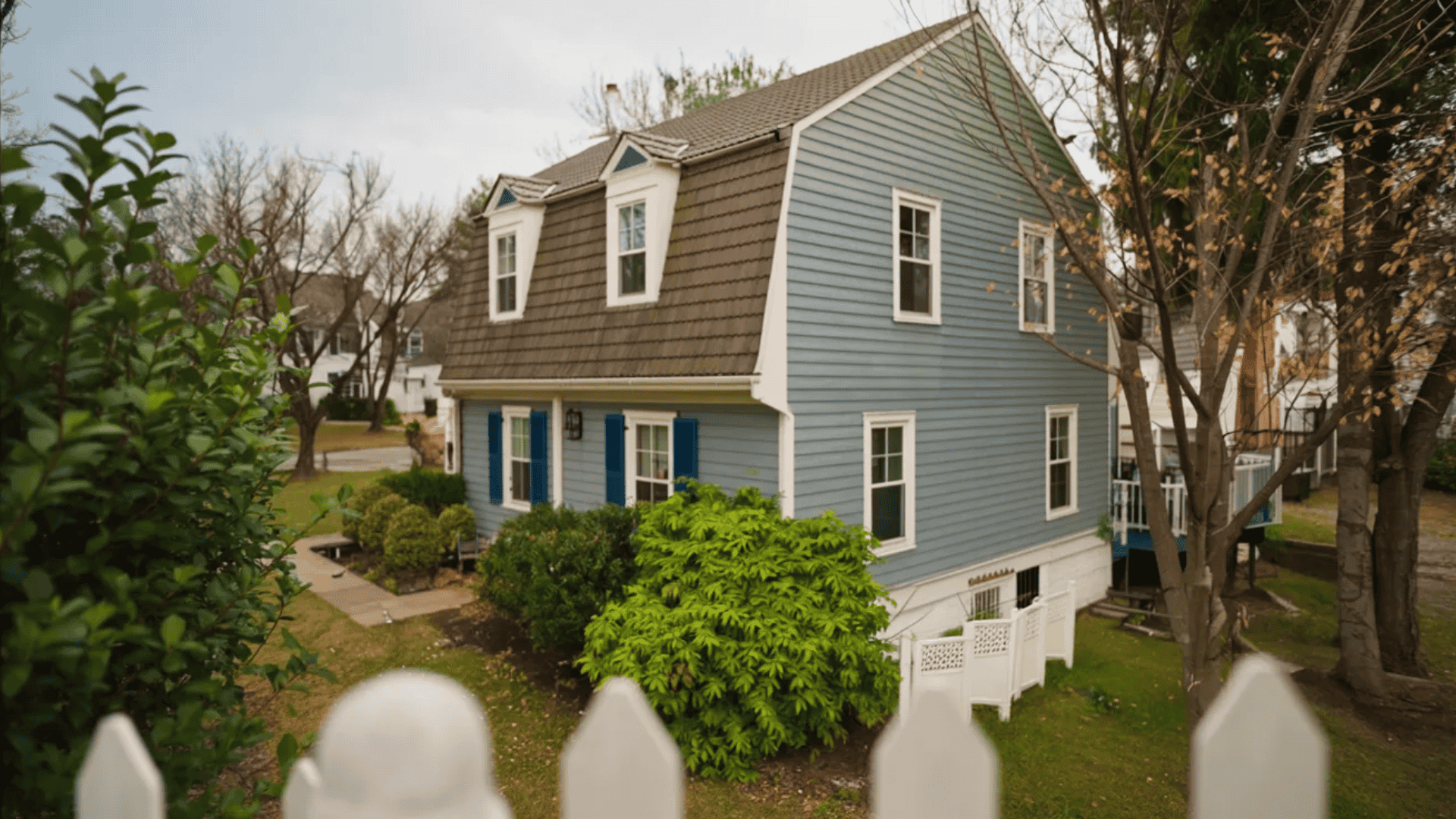 A charming blue house bordered by a white picket fence