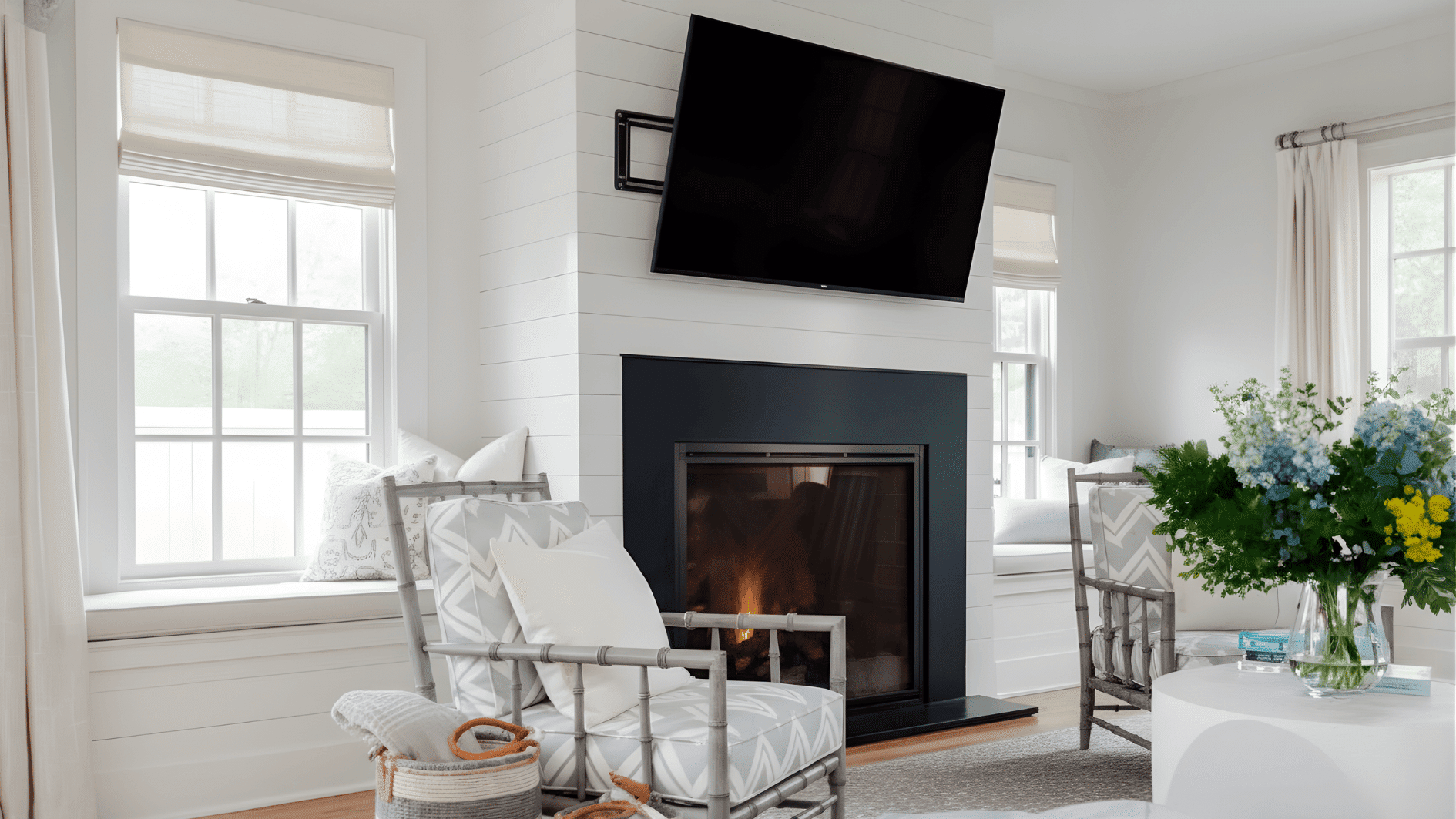 A living room featuring white walls, a fireplace, and a TV mounted above the low mantel, tilted for optimal viewing.