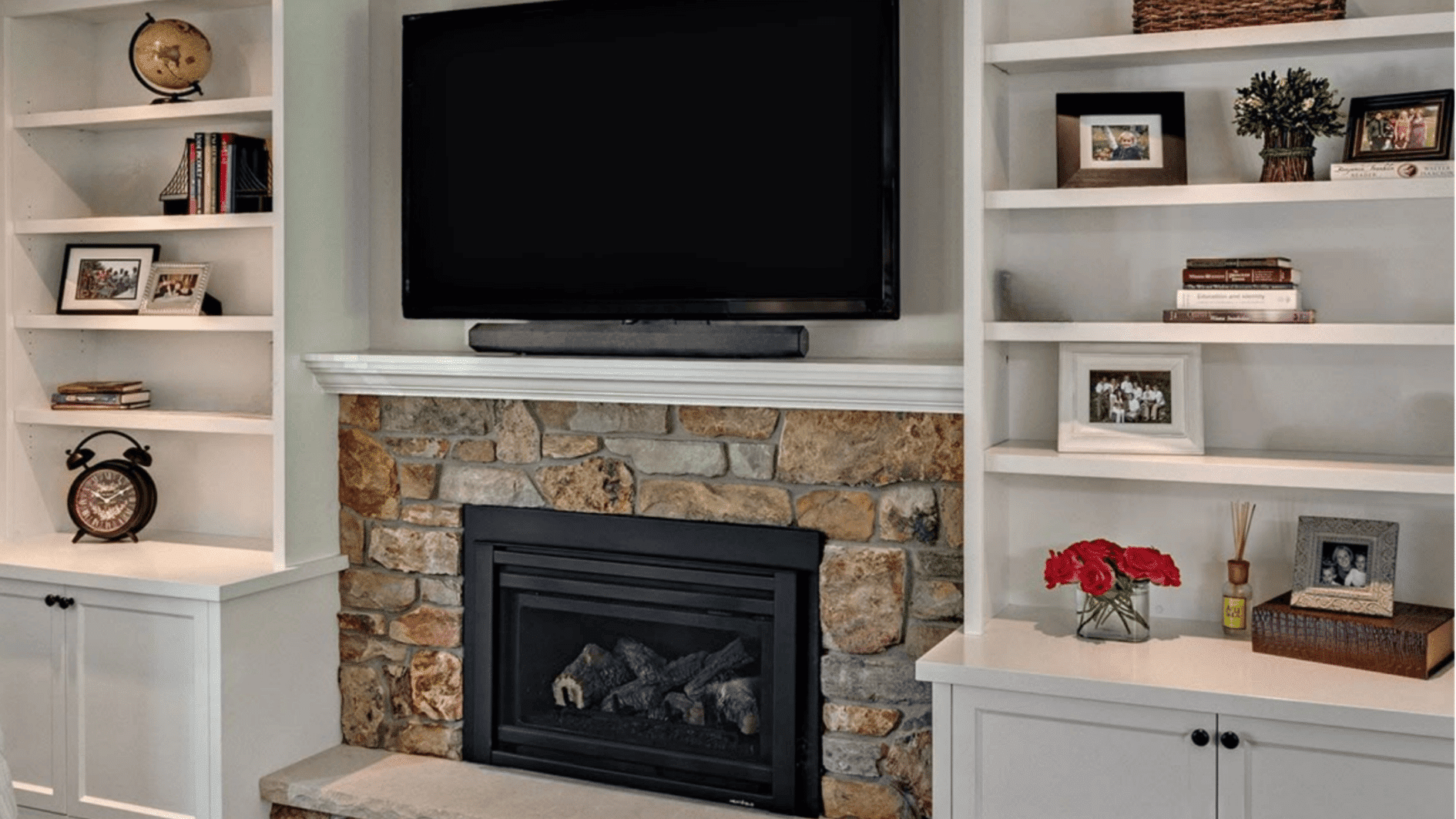 A modern fireplace with built-in shelves and a flat screen TV, providing organized storage for media equipment and accessories.