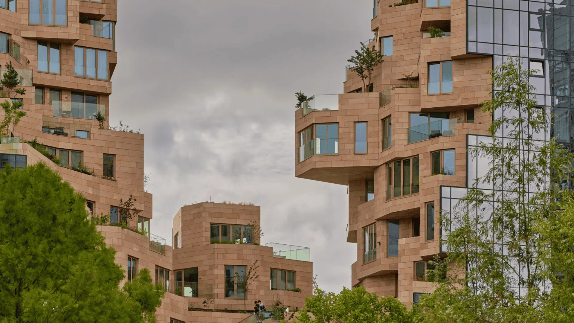 A multi-story building featuring numerous windows and balconies on its facade which provides it a dense look with clear sky.