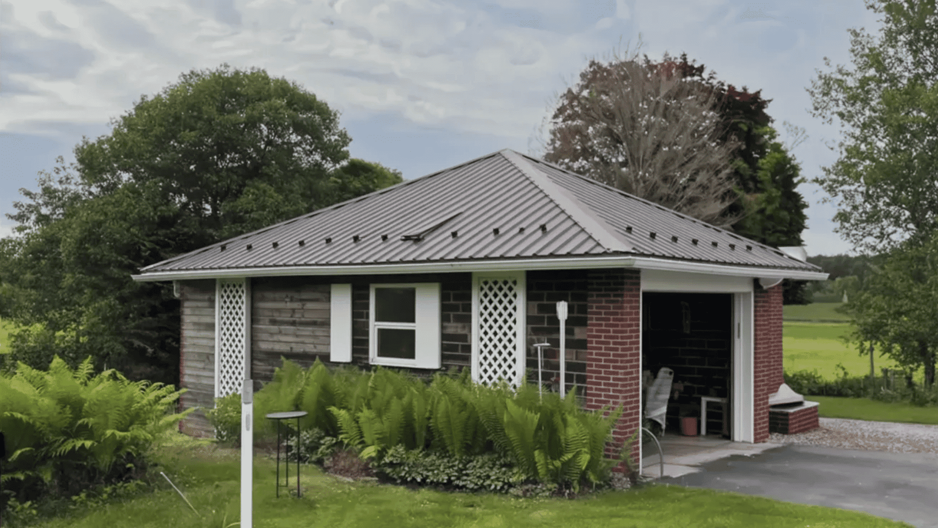 A small brick building featuring a metal roof, set against a clear sky
