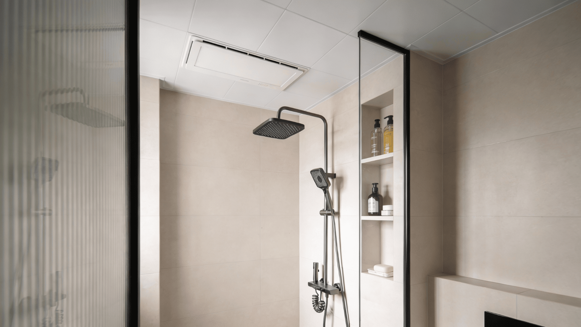 A small walk in shower with a ceiling mounted rainhead, built in wall niche shelves, and a slim glass panel for an open feel