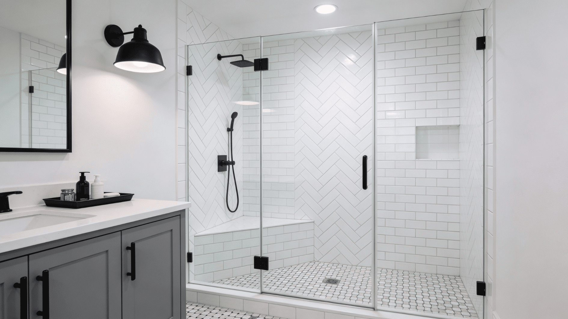 Compact walk in shower with a small tiled corner bench, clear glass door, and white herringbone walls with black fixtures