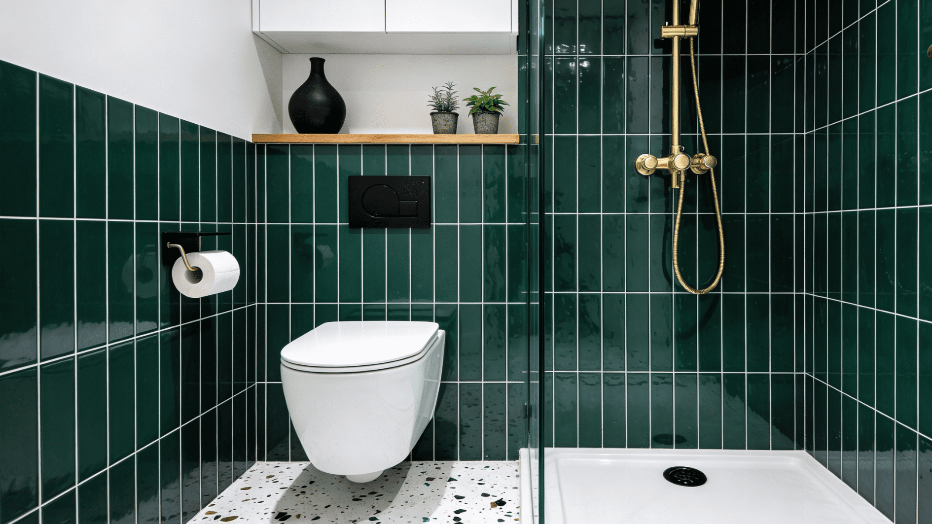 Modern walk in shower with tall vertical green tiles, a wall hung toilet, gold fixtures, and a clean white shelf for storage