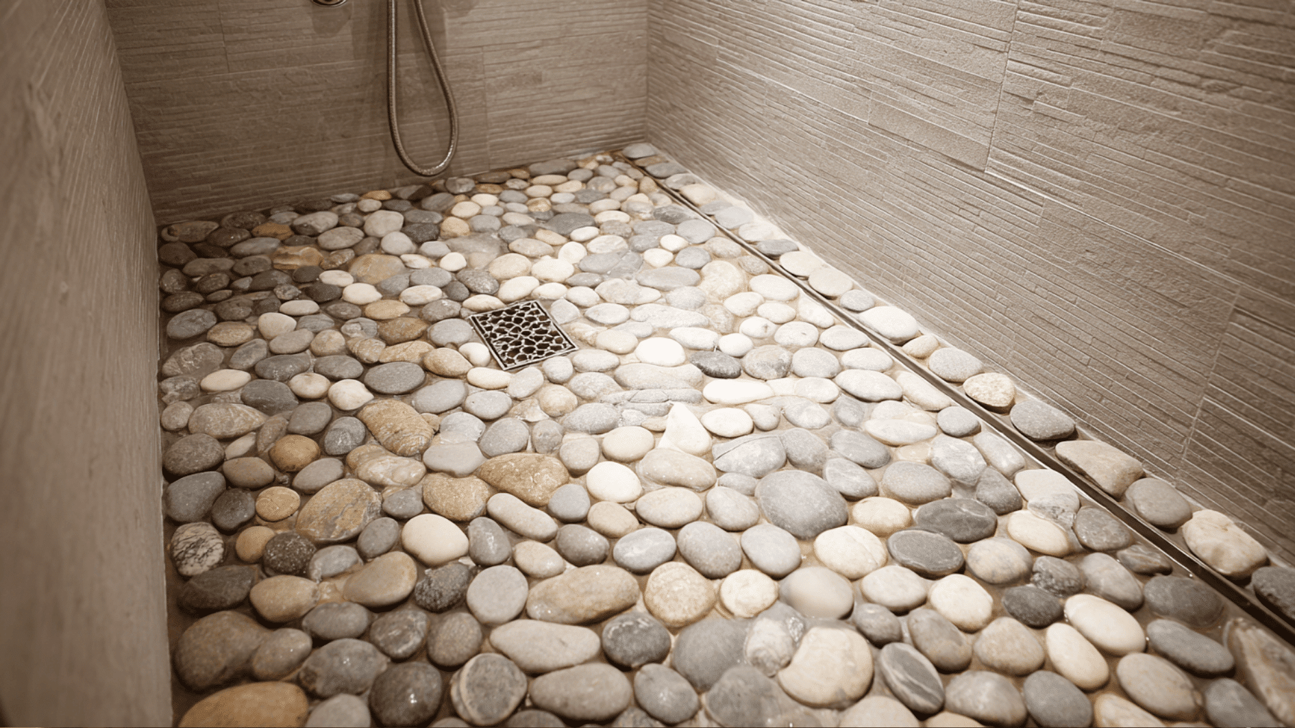 Pebble look shower flooring adds grip and texture, while neutral stones create a natural spa feel in a small walk in shower