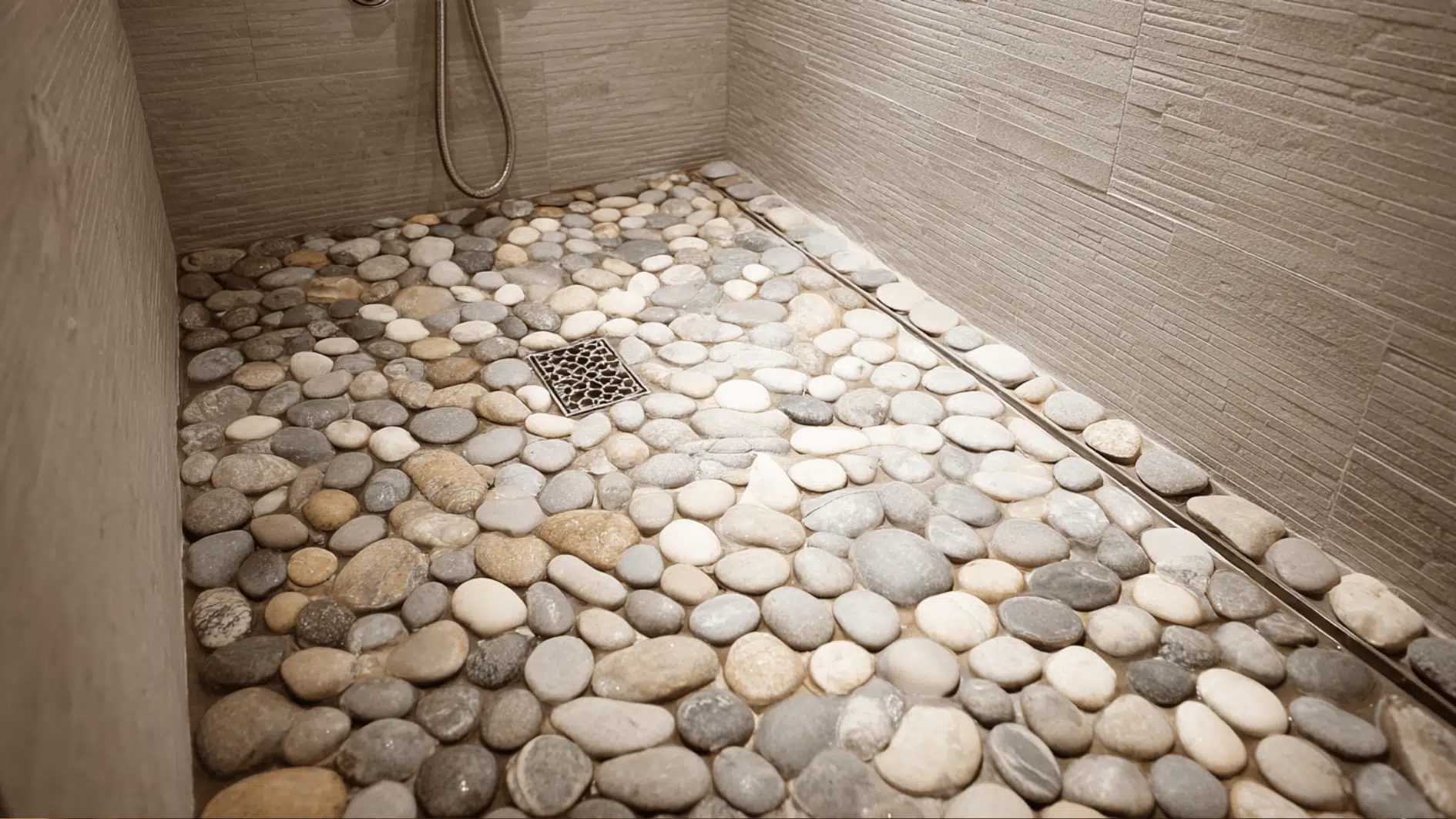 Pebble look shower flooring adds grip and texture, while neutral stones create a natural spa feel in a small walk in shower