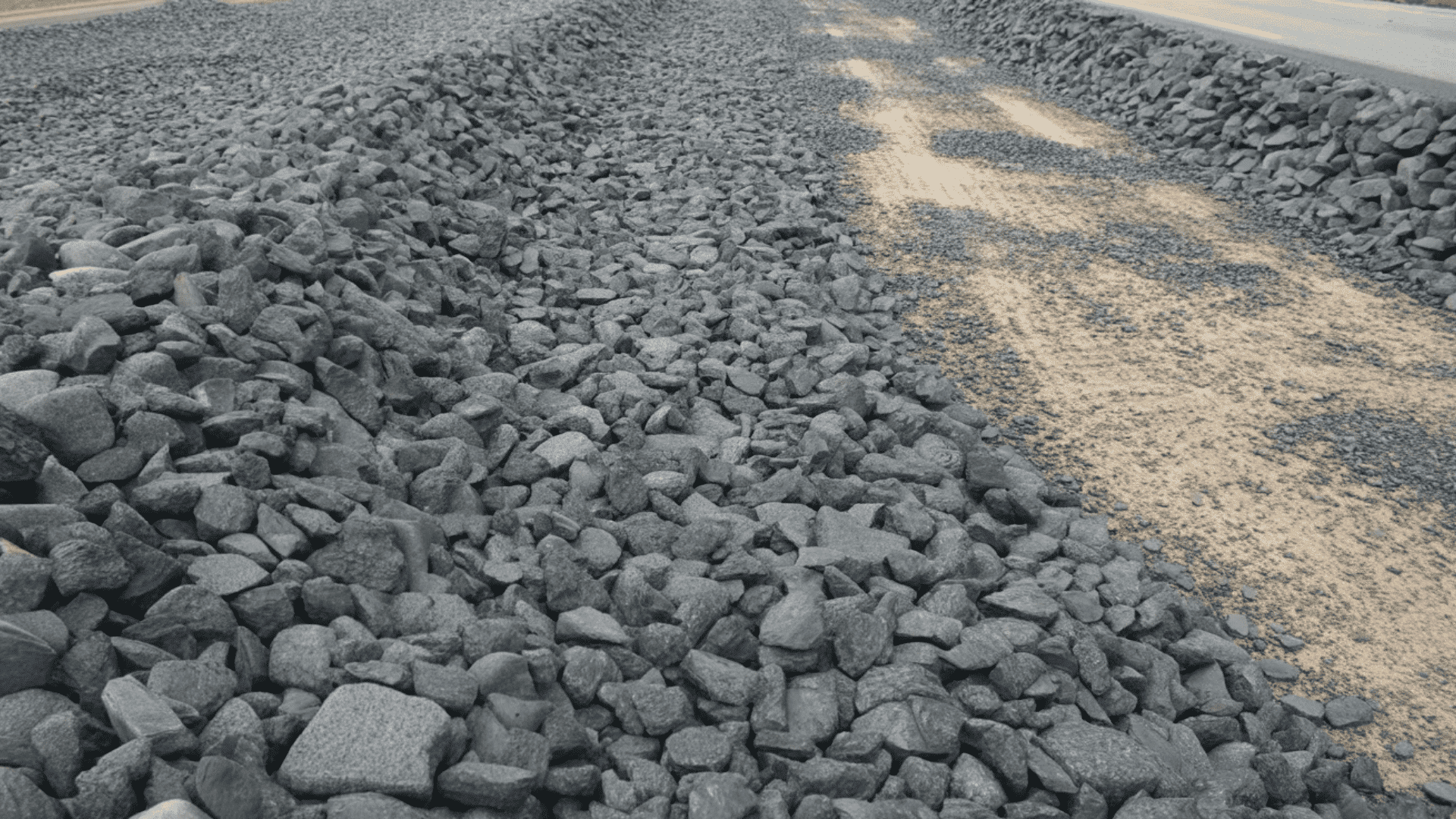 A train travels along a track, flanked by rocks on either side, showcasing a scenic railway environment