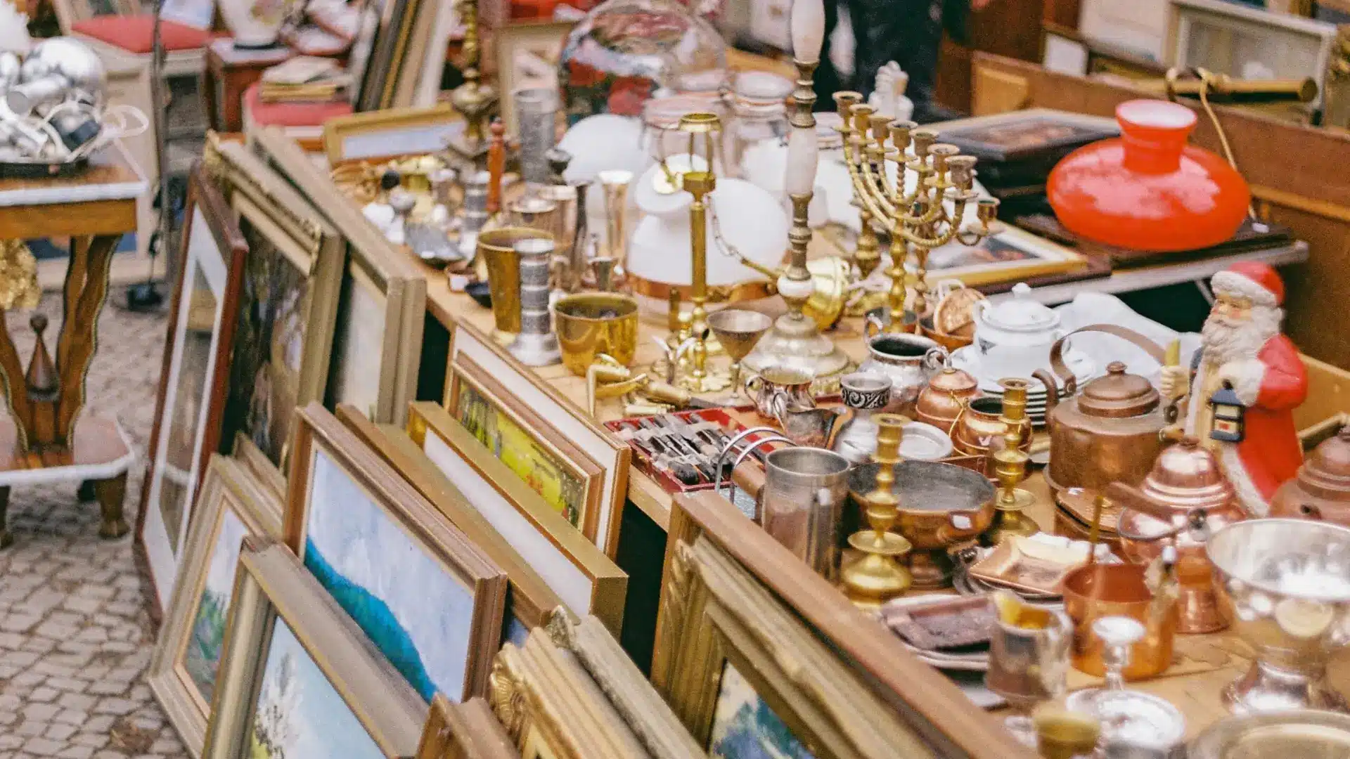 Antique market stall in Isle-sur-la-Sorgue filled with vintage frames, brassware, ceramics, and decorative collectibles