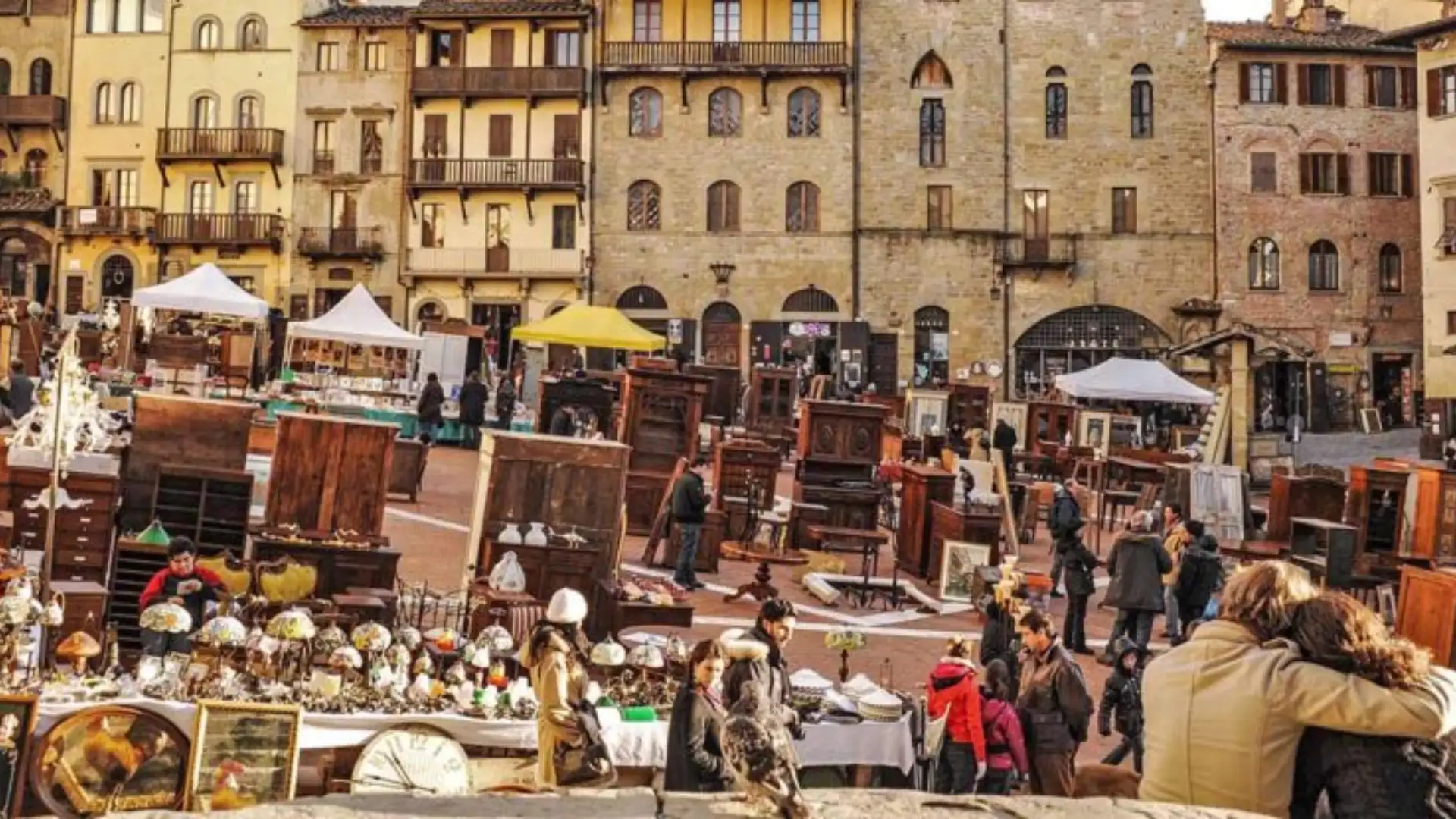 Arezzo Antiques Fair in Tuscany with vintage furniture, art, and crowds browsing stalls in a historic piazza