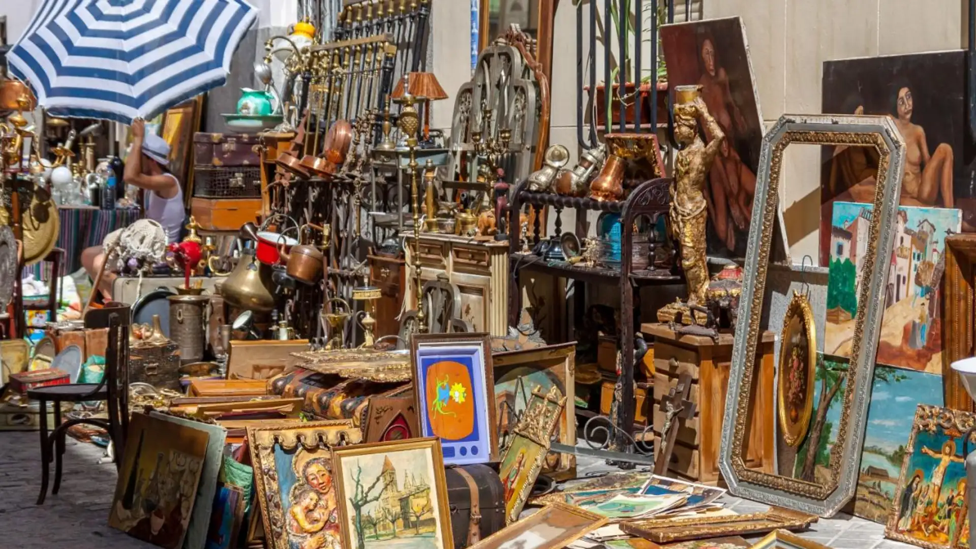 El Rastro market in Madrid with eclectic antiques, paintings, mirrors, and vintage items displayed along lively street stalls