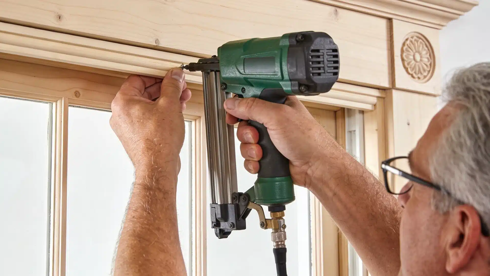 A man uses a nail gun to secure a window frame during a home renovation project.