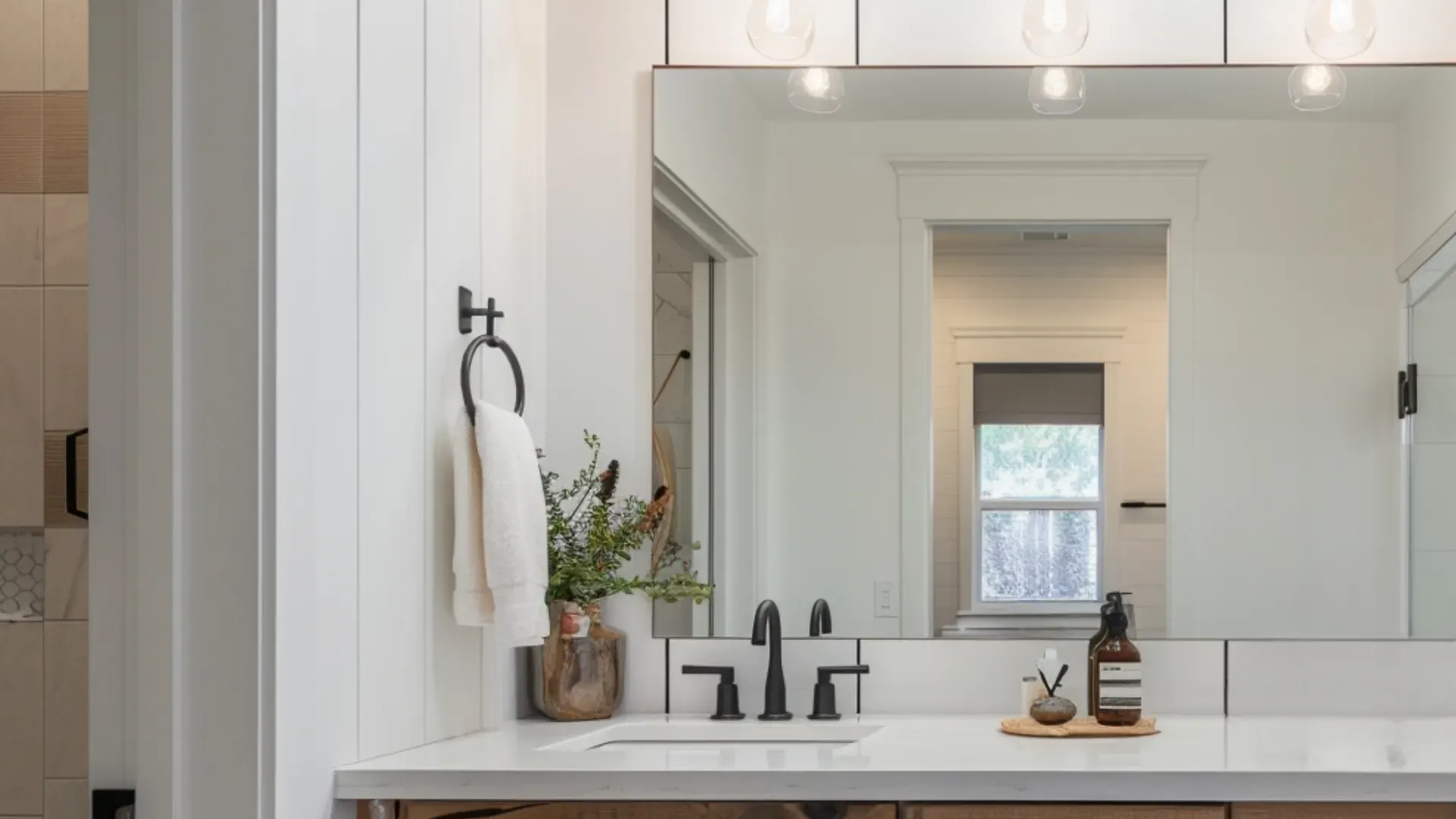 Small bathroom with oversized frameless mirror and warm LED lighting