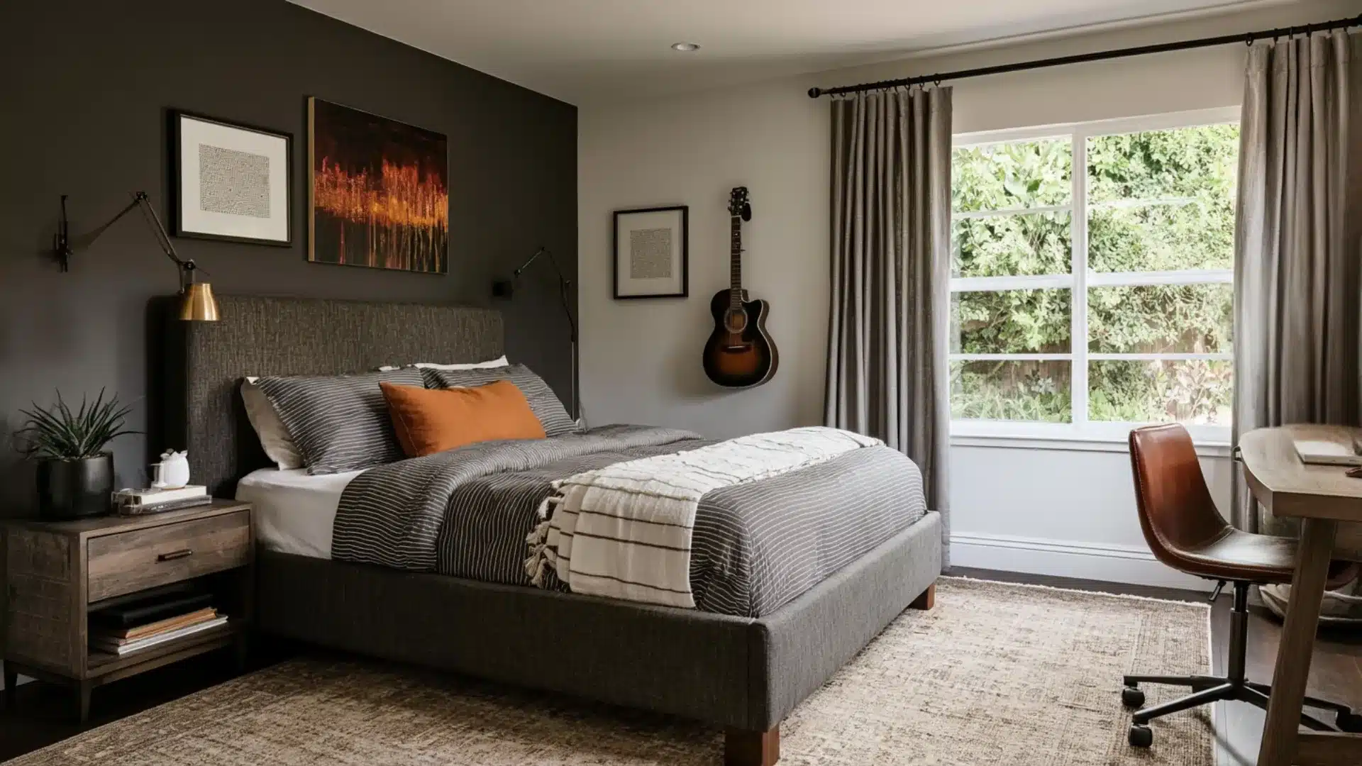 Bedroom with a gray upholstered bed, striped bedding and orange pillow, guitar, desk and chair, window, curtains, and bedside table.