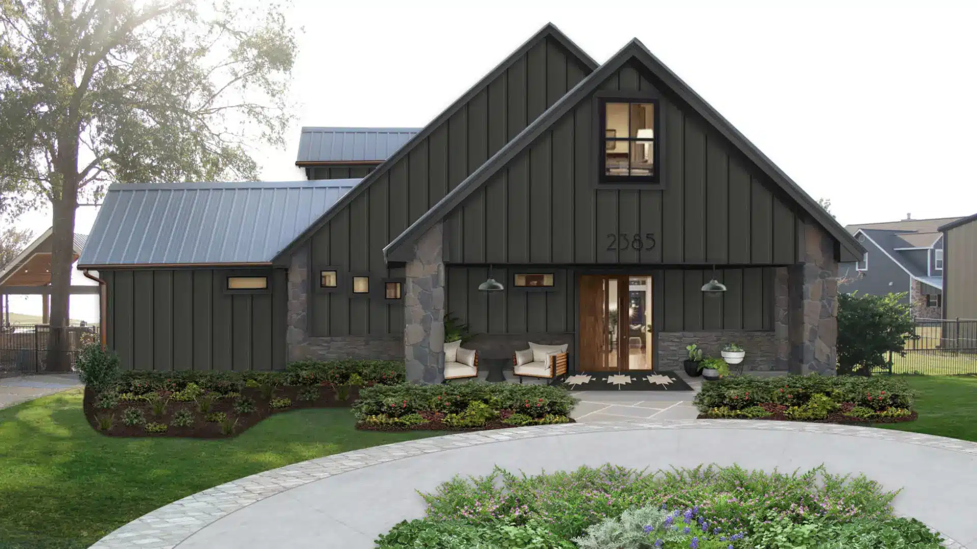 Modern dark gray gabled house with stone accents, landscaped flower beds, outdoor seating, and a curved concrete driveway.