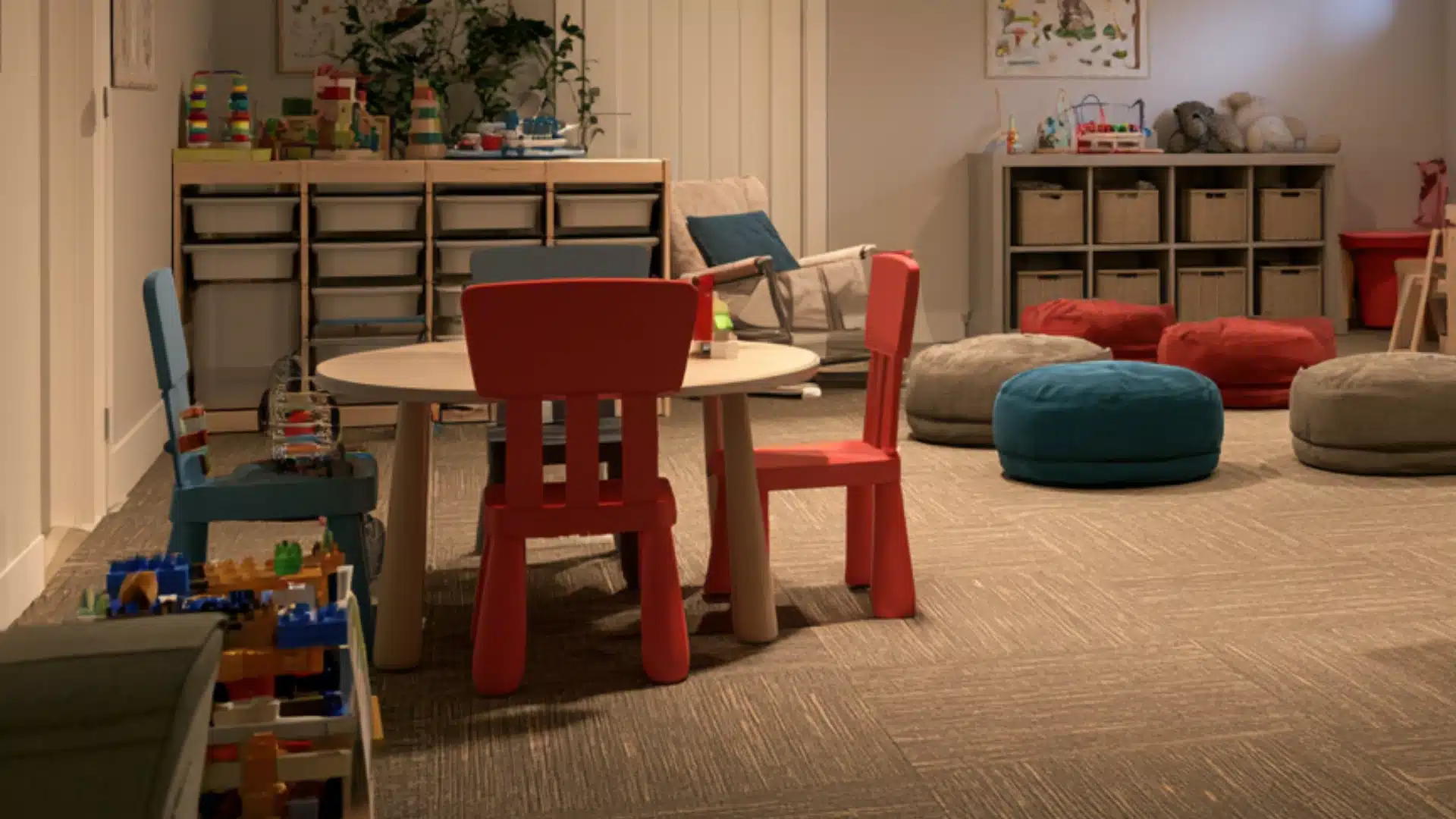 Colorful finished basement playroom with children table chairs storage bins toys floor cushions and a cozy reading area