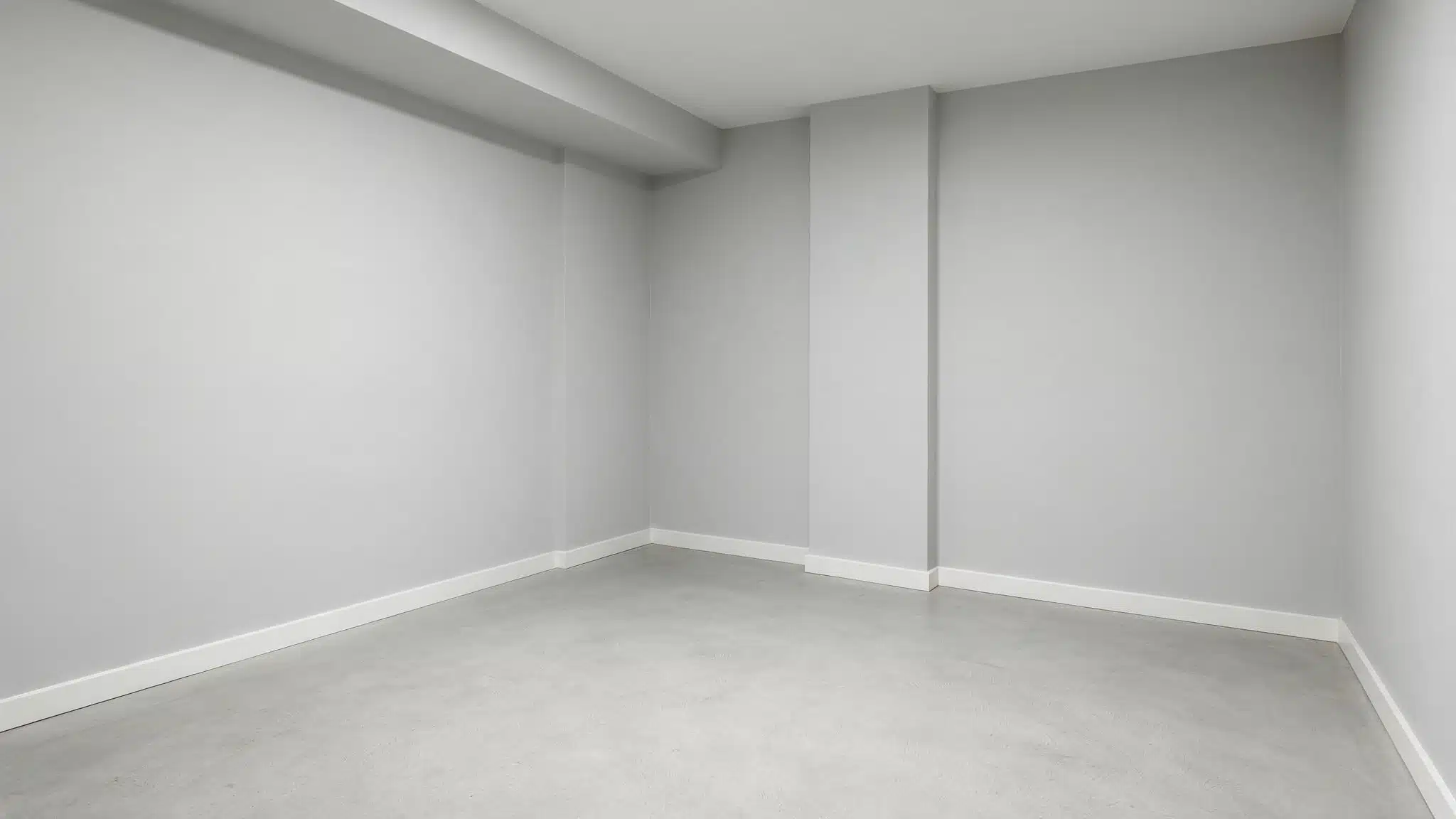 Empty basement room with smooth light gray concrete floor pale gray walls white trim and simple clean finish throughout