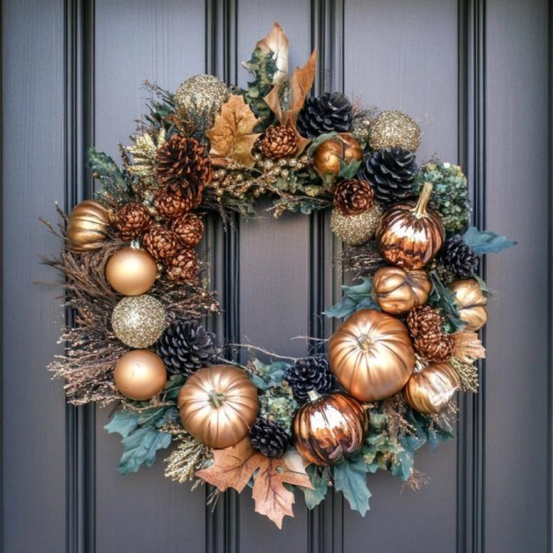 DIY fall wreath with metallic pumpkins, pine cones, gold ornaments, autumn leaves, and greenery on a dark paneled front door.