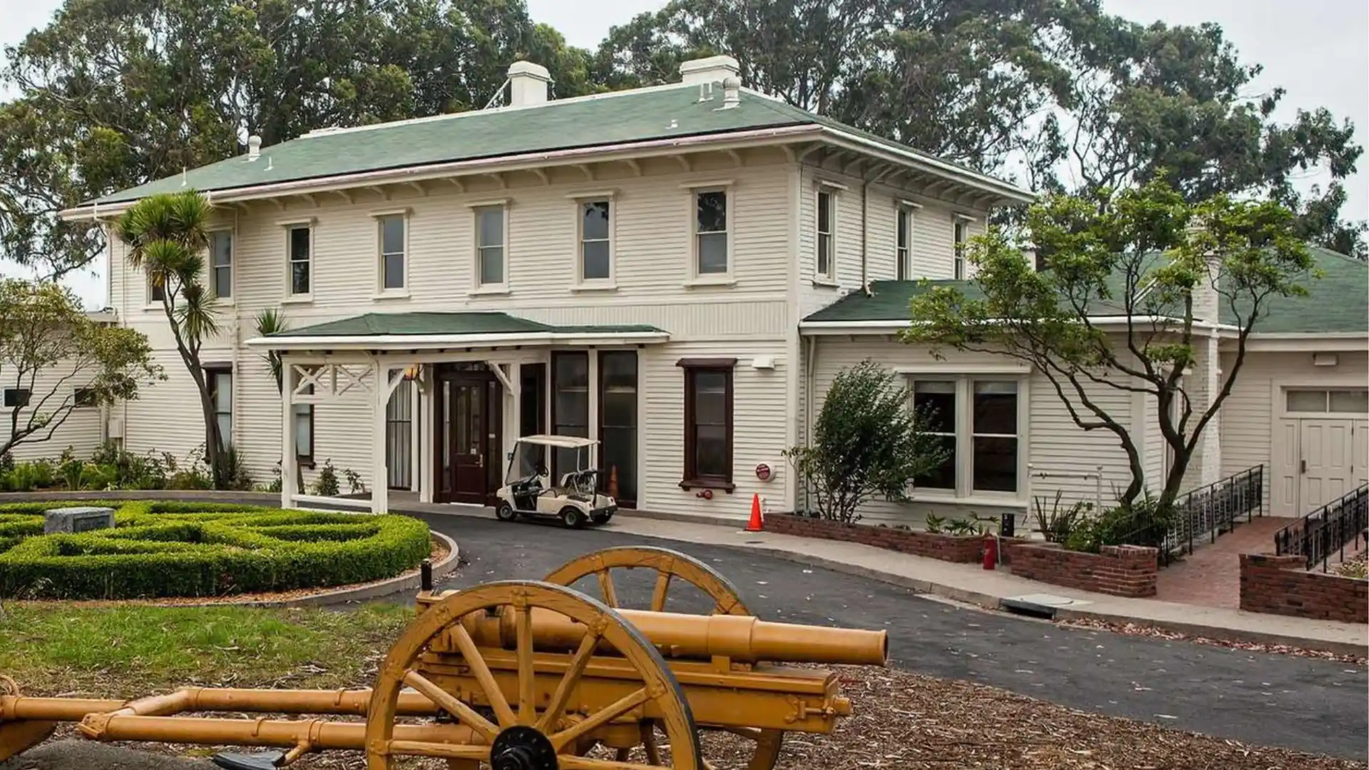 Historic Italianate officers club with clapboard siding low hipped roof wide eaves tall windows and front porch