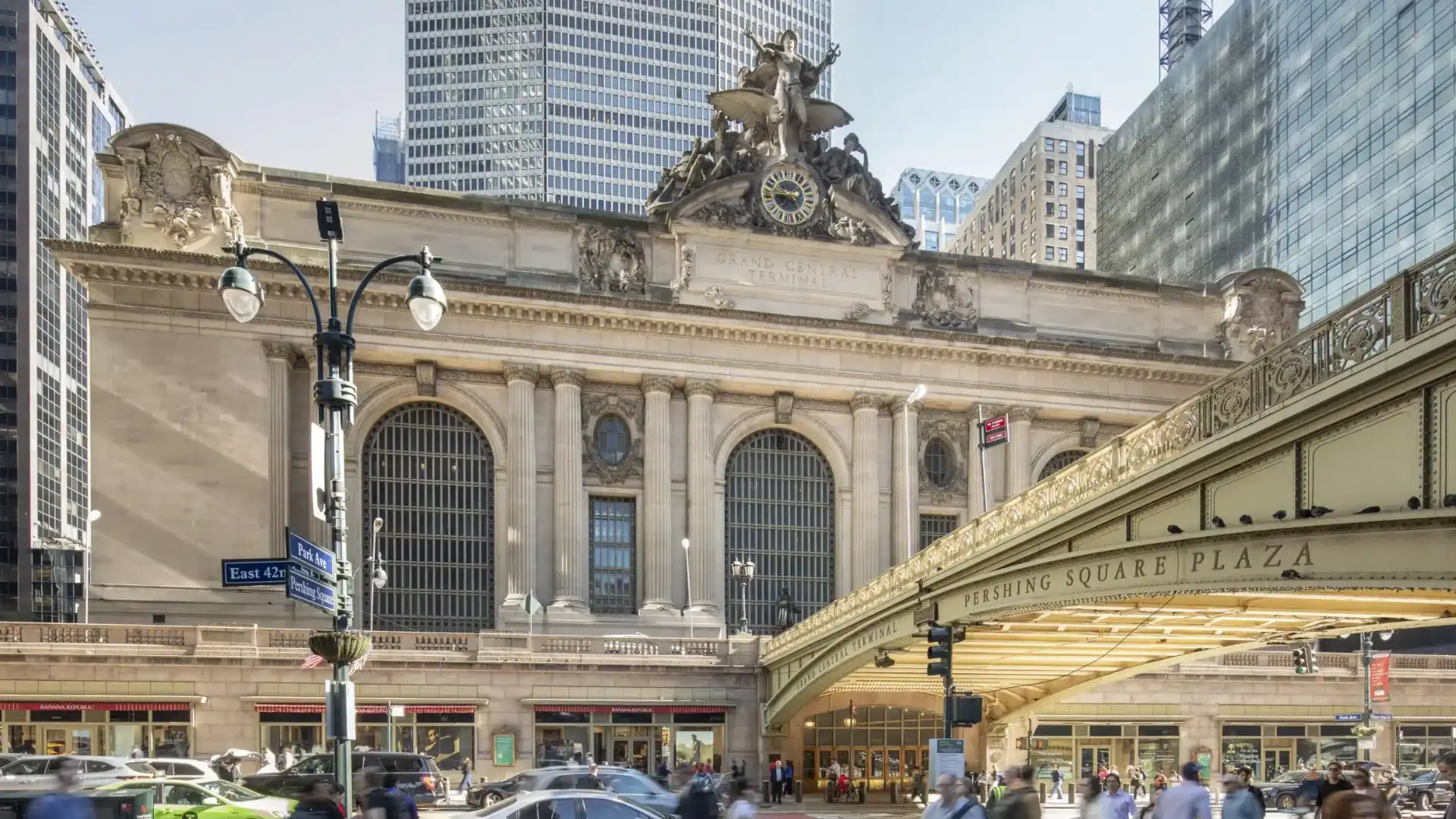 Grand Central Terminal exterior with tall arched windows classical columns rooftop sculptures and busy city streets
