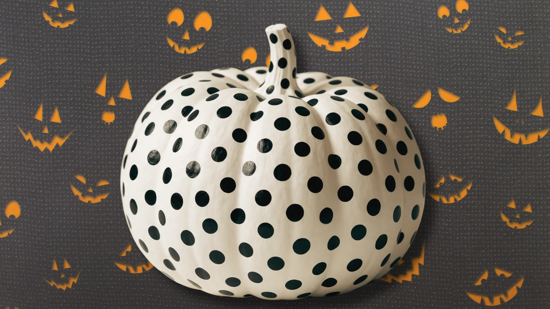 White pumpkin painted with a dense pattern of black polka dots all over its surface.