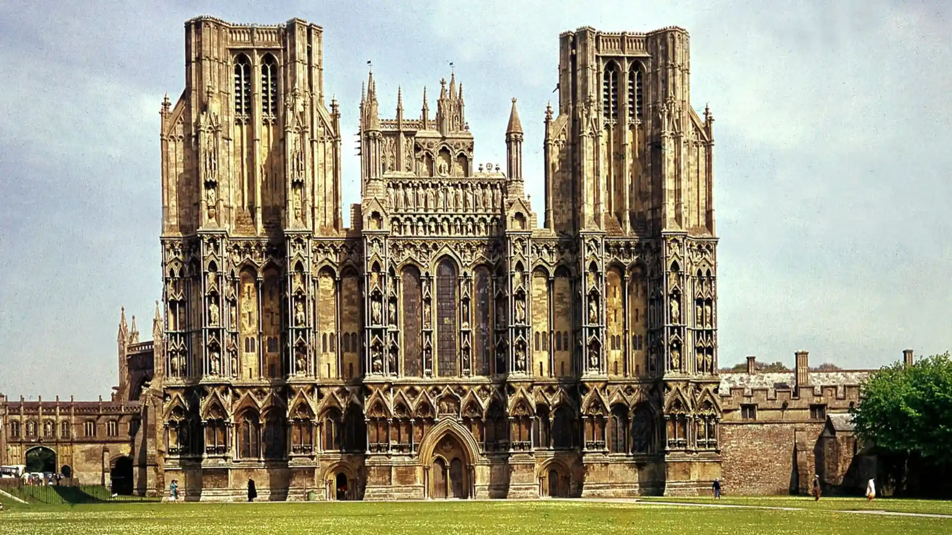 Gothic cathedral with twin towers and ornate stone carvings on a grassy courtyard