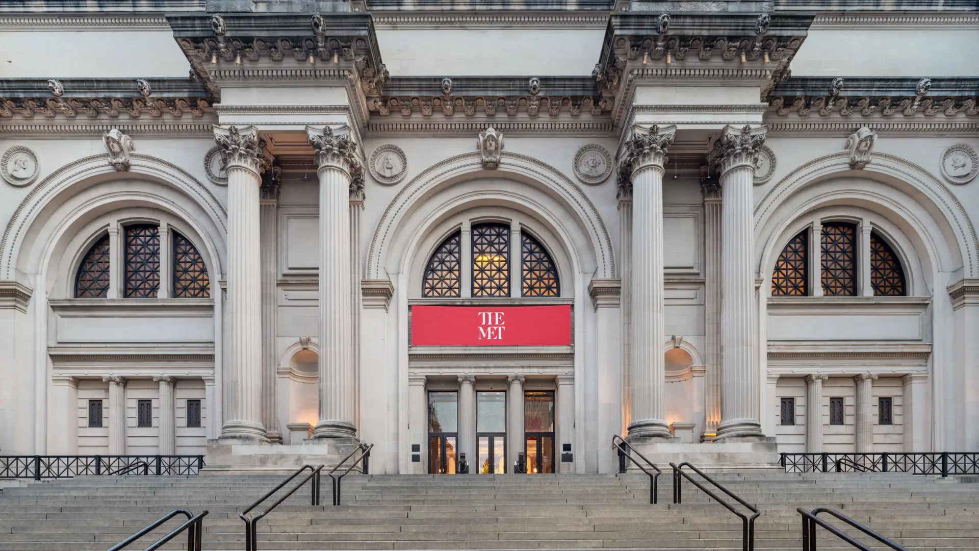 Metropolitan Museum of Art entrance with tall Corinthian columns arched windows wide stone steps medallions and carved cornices