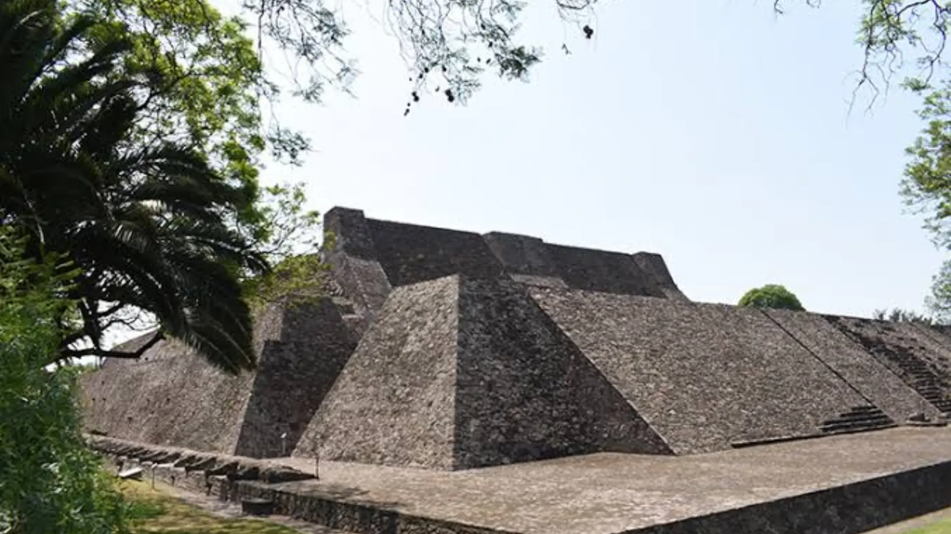 Tenayuca archaeological site showing an ancient stone pyramid surrounded by trees and greenery.