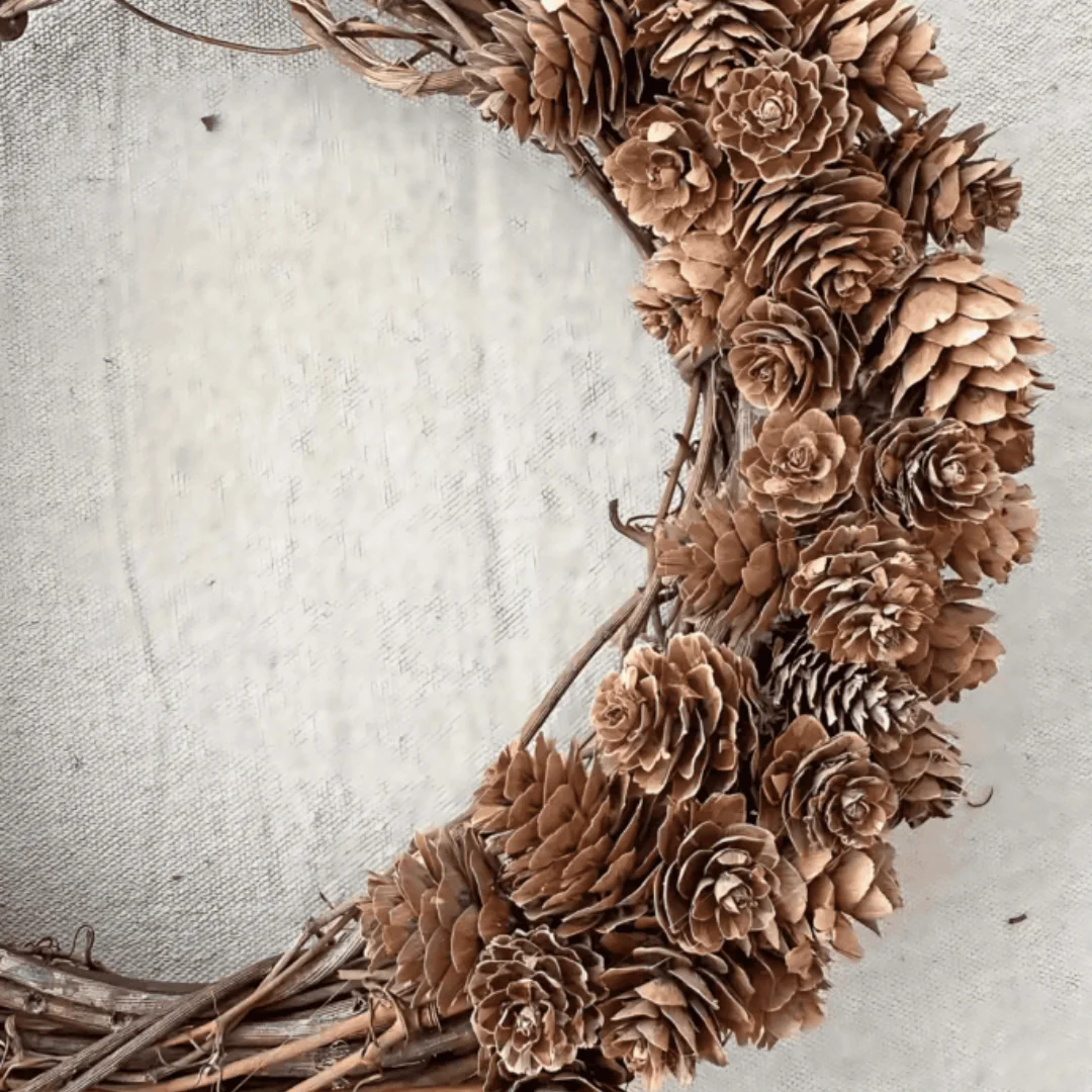 DIY pine cone wreath made with layered natural pine cones and grapevine, creating a simple woodland-style fall decoration.